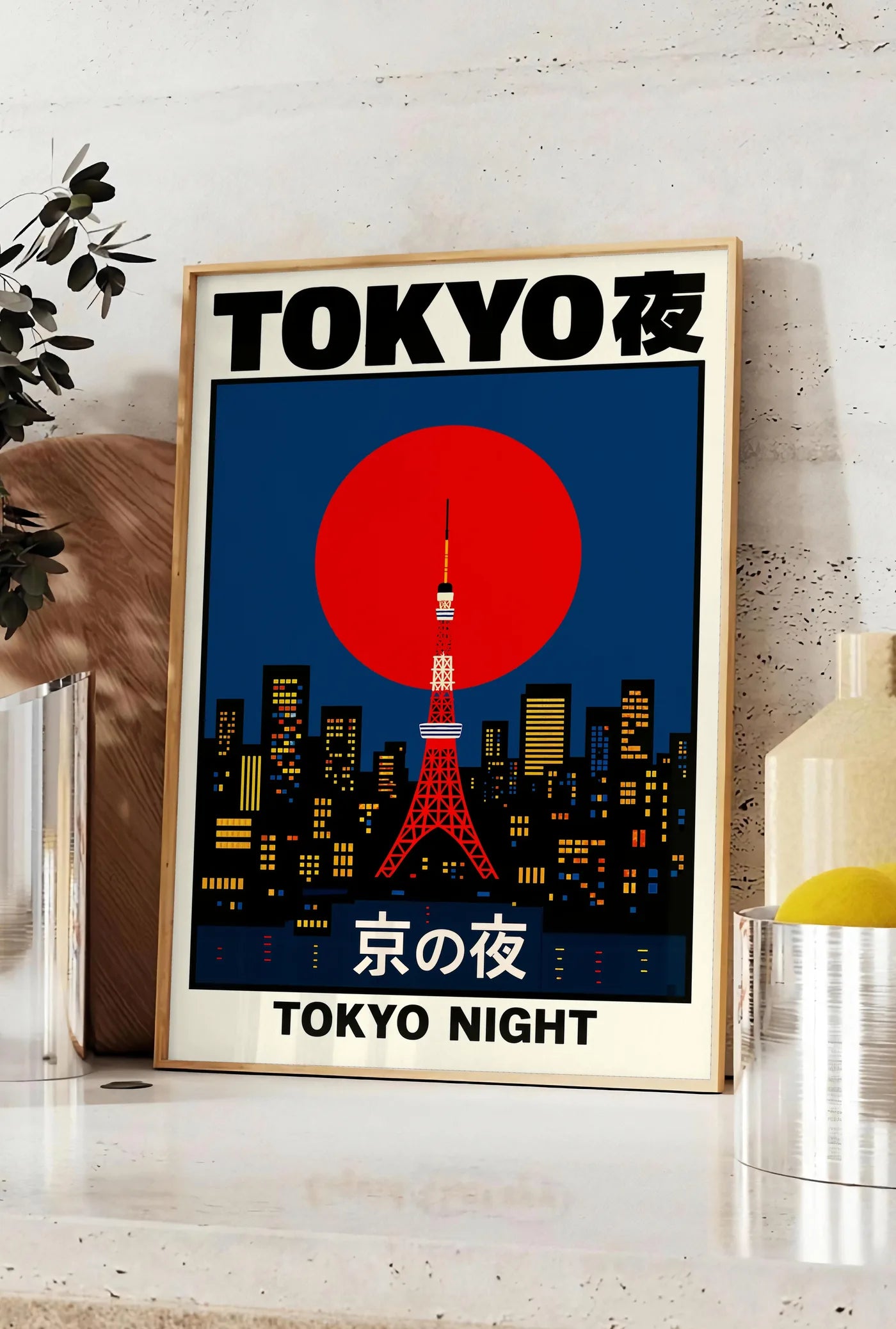 Affiche affiche tour de Tokyo et soleil rouge art japonais, posee sur un plan de travail de cuisine en pierre claire, entre une branche d'eucalyptus en vase et un bocal de citrons