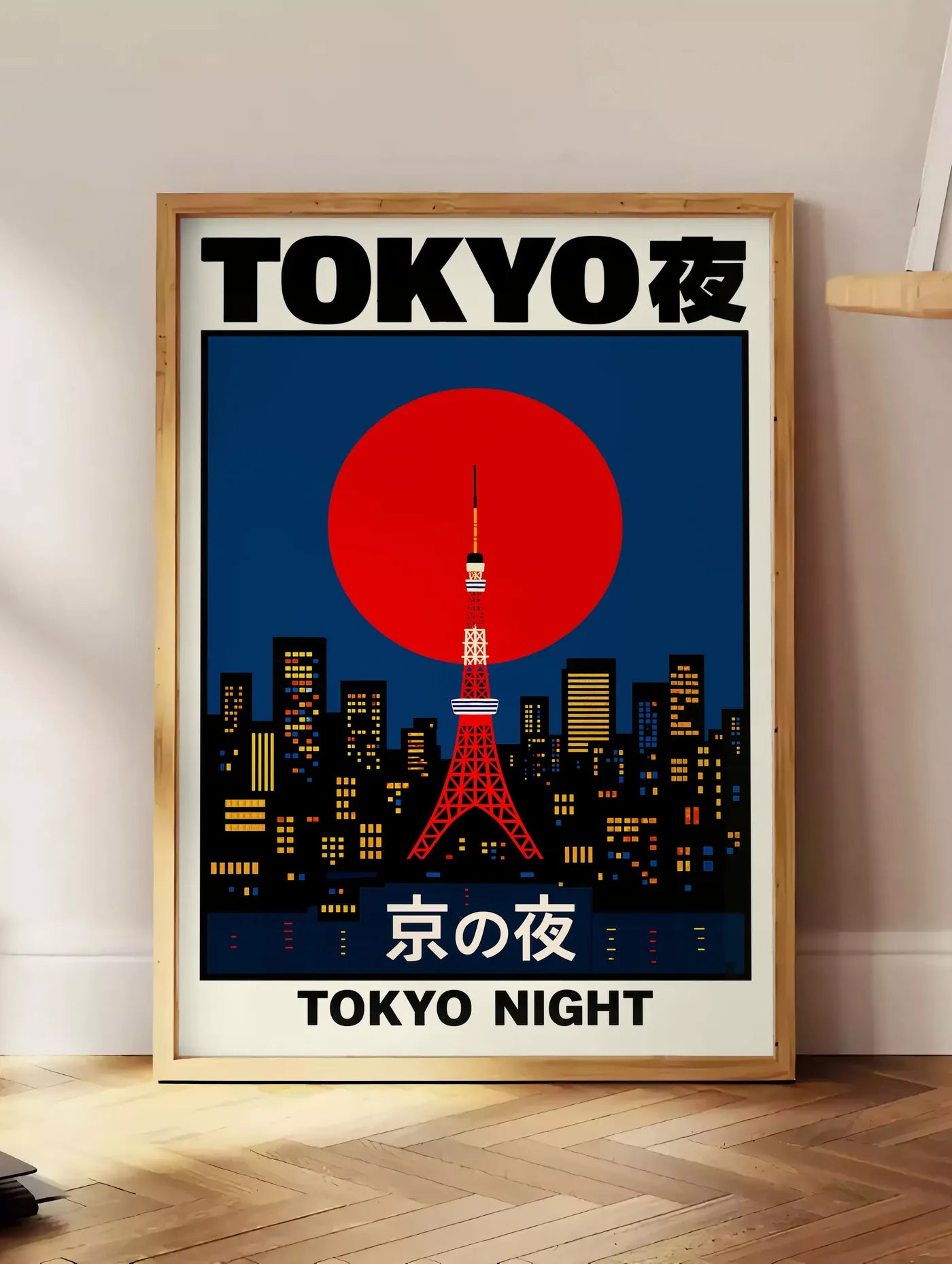 Estampe affiche tour de Tokyo et soleil rouge art japonais, posee au sol dans un coin salon, sur un parquet a chevrons, pres d'une table d'appoint en chene chargee de livres