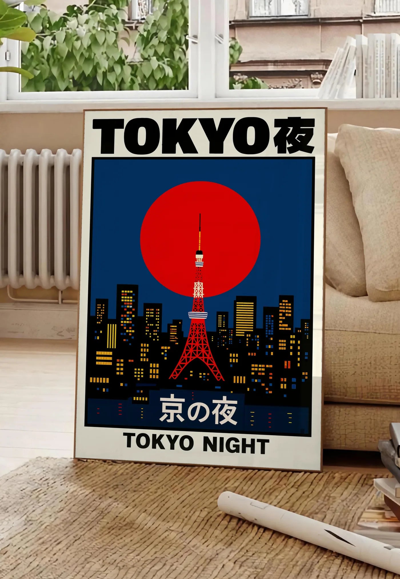 Poster affiche tour de Tokyo et soleil rouge art japonais, posee au sol dans un salon parisien, devant une grande fenetre donnant sur un immeuble haussmannien, entre un ficus et un canape creme