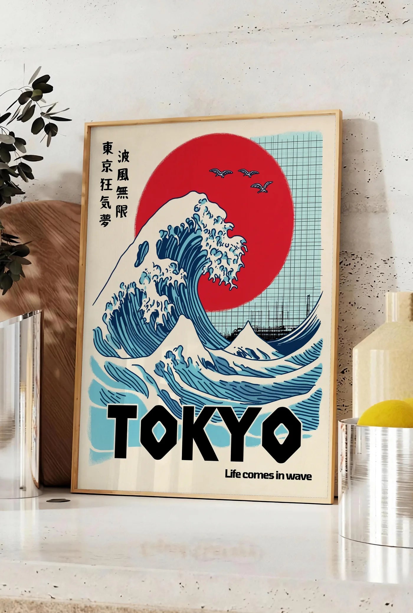 Affiche affiche vague de Tokyo et soleil rouge art japonais, posee sur un plan de travail de cuisine en pierre claire, entre une branche d'eucalyptus en vase et un bocal de citrons