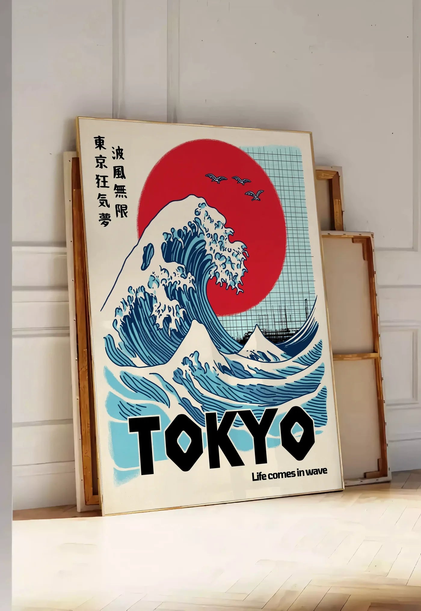 Tirage encadrable affiche vague de Tokyo et soleil rouge art japonais, posee au sol dans une entree lumineuse, contre un mur a panneaux blancs, a cote de chassis en bois empiles