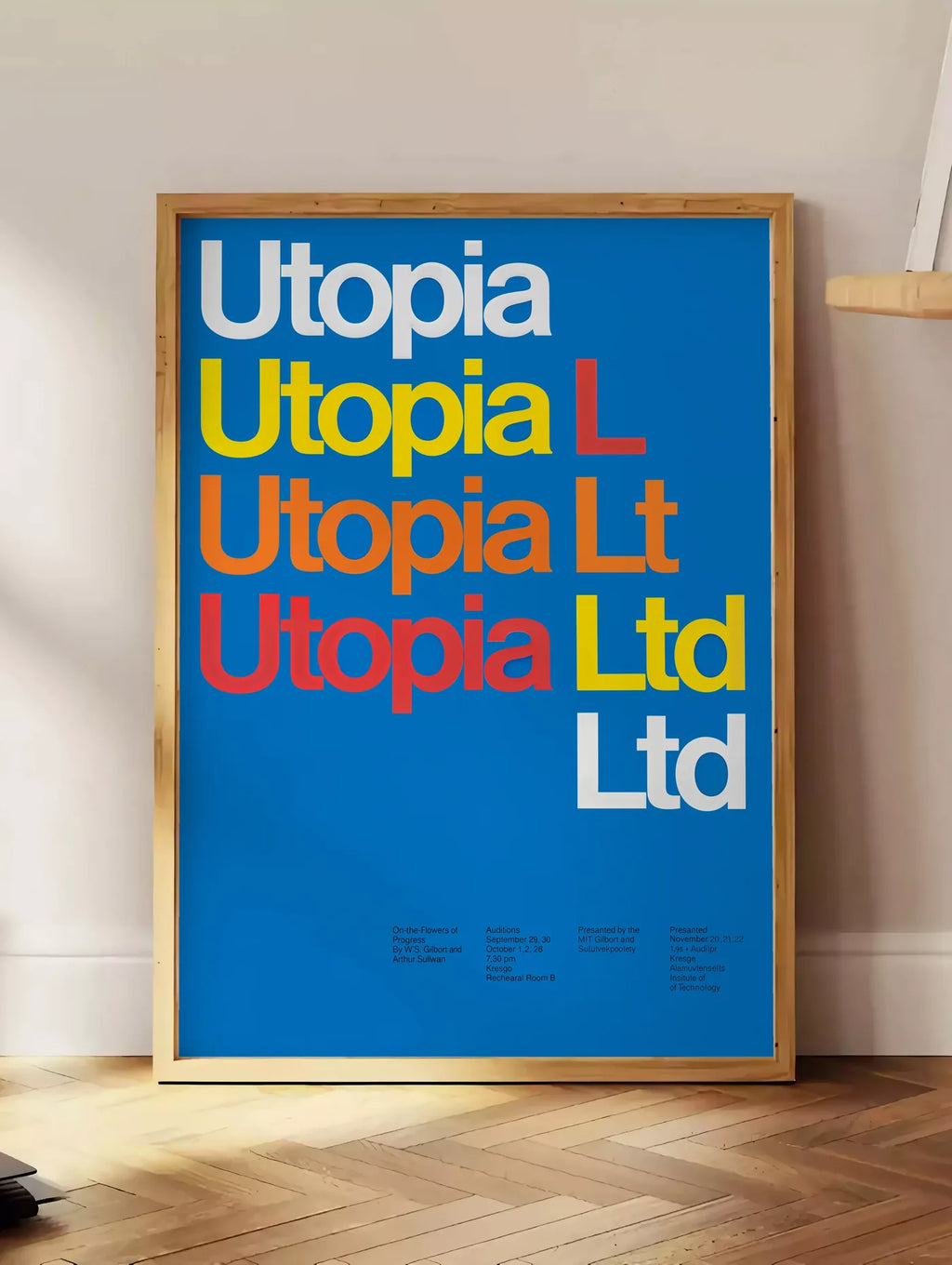 Estampe typographie Utopia Ltd repetee en blanc jaune et rouge sur bleu, posee au sol dans un coin salon, sur un parquet a chevrons, pres d'une table d'appoint en chene chargee de livres