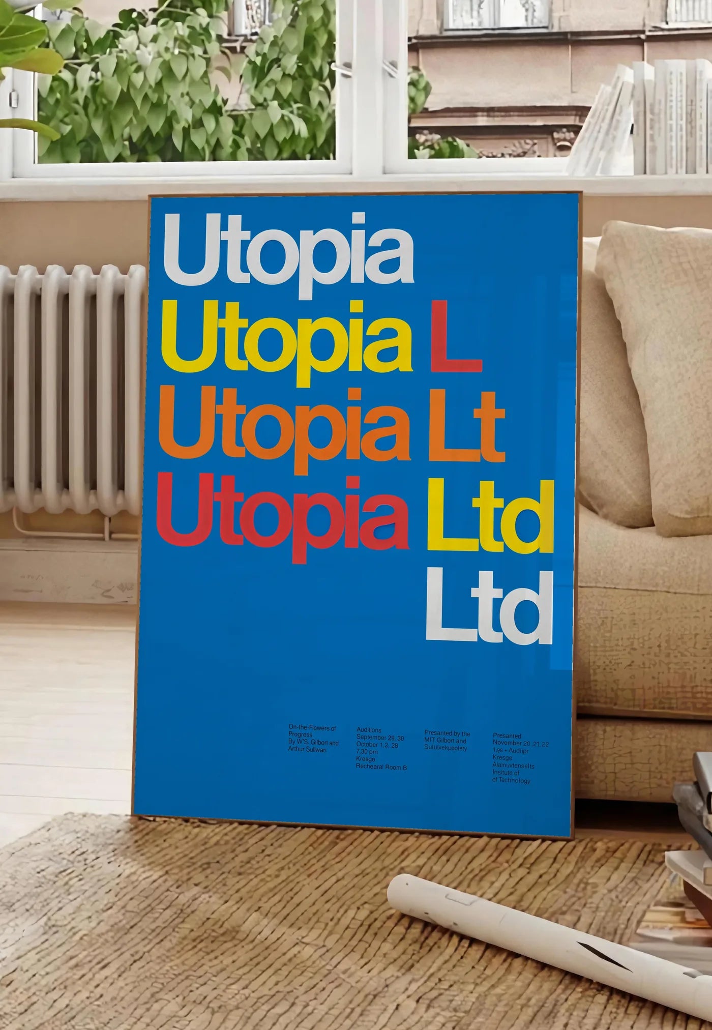 Poster typographie Utopia Ltd repetee en blanc jaune et rouge sur bleu, posee au sol dans un salon parisien, devant une grande fenetre donnant sur un immeuble haussmannien, entre un ficus et un canape creme