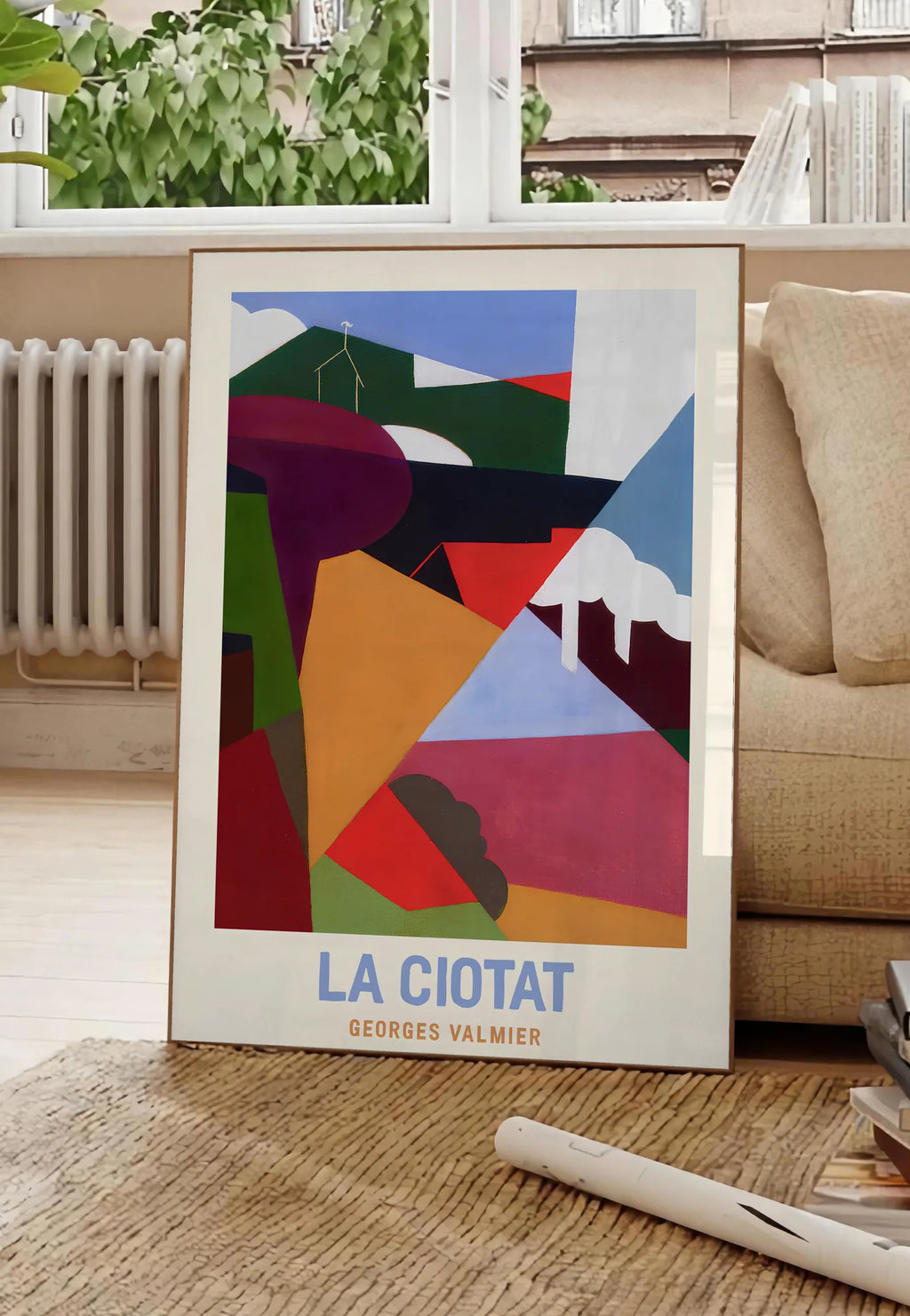 Poster affiche La Ciotat cubiste, posee au sol dans un salon parisien, devant une grande fenetre donnant sur un immeuble haussmannien, entre un ficus et un canape creme