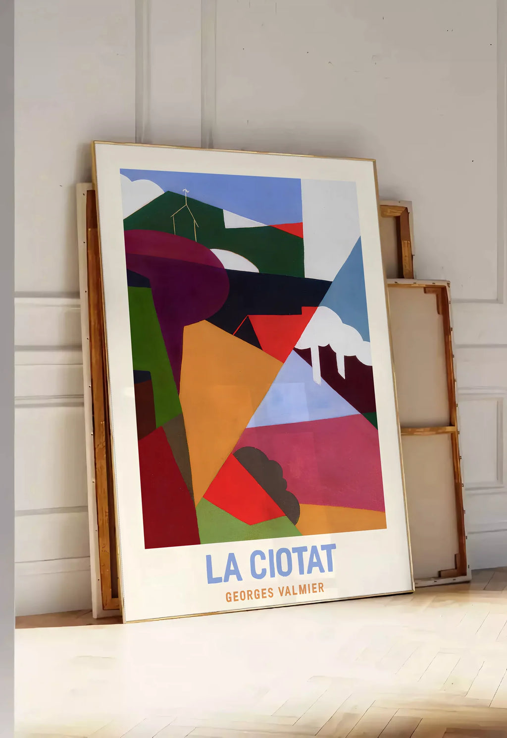 Tirage encadrable affiche La Ciotat cubiste, posee au sol dans une entree lumineuse, contre un mur a panneaux blancs, a cote de chassis en bois empiles