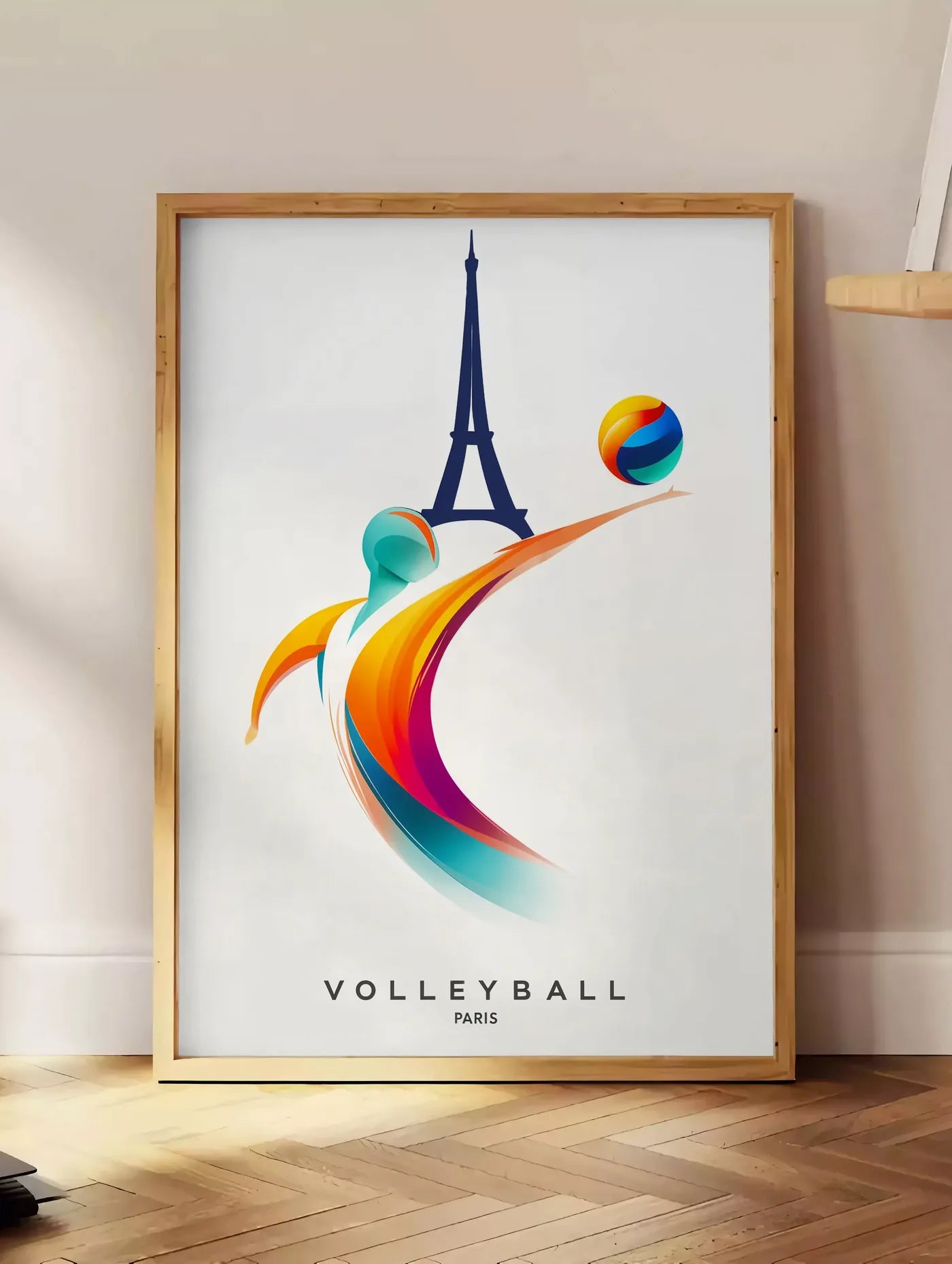 Estampe joueur de volley stylisé devant la silhouette de la Tour Eiffel, posee au sol dans un coin salon, sur un parquet a chevrons, pres d'une table d'appoint en chene chargee de livres