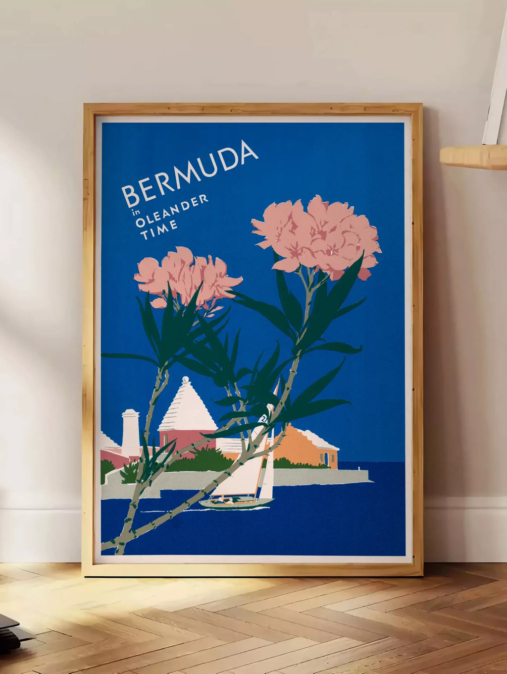 Estampe affiche Bermudes vintage, posee au sol dans un coin salon, sur un parquet a chevrons, pres d'une table d'appoint en chene chargee de livres
