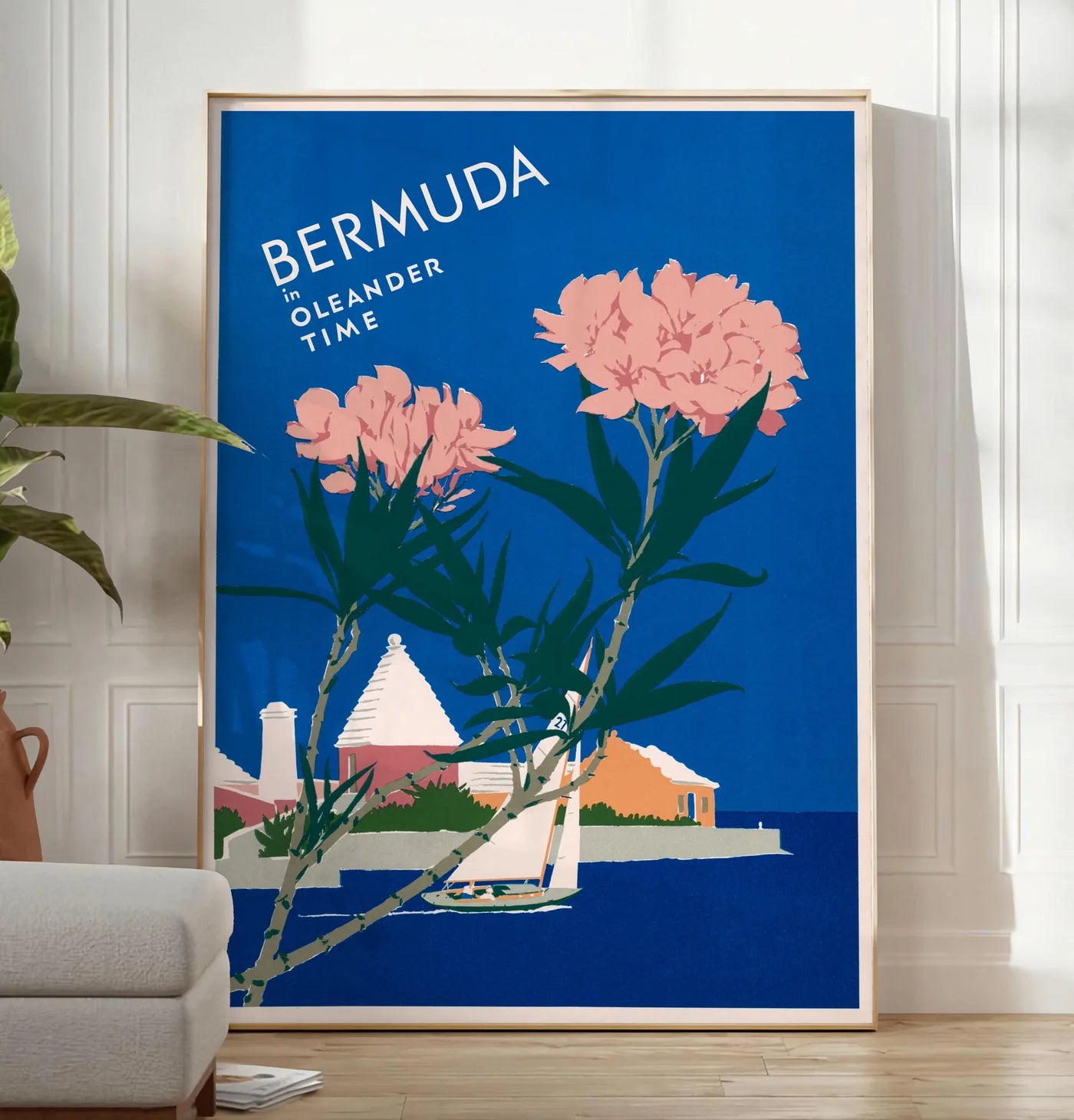 Reproduction affiche Bermudes vintage, posee au sol dans un salon minimaliste clair, a cote d'un canape beige et d'une plante verte, sur un parquet clair