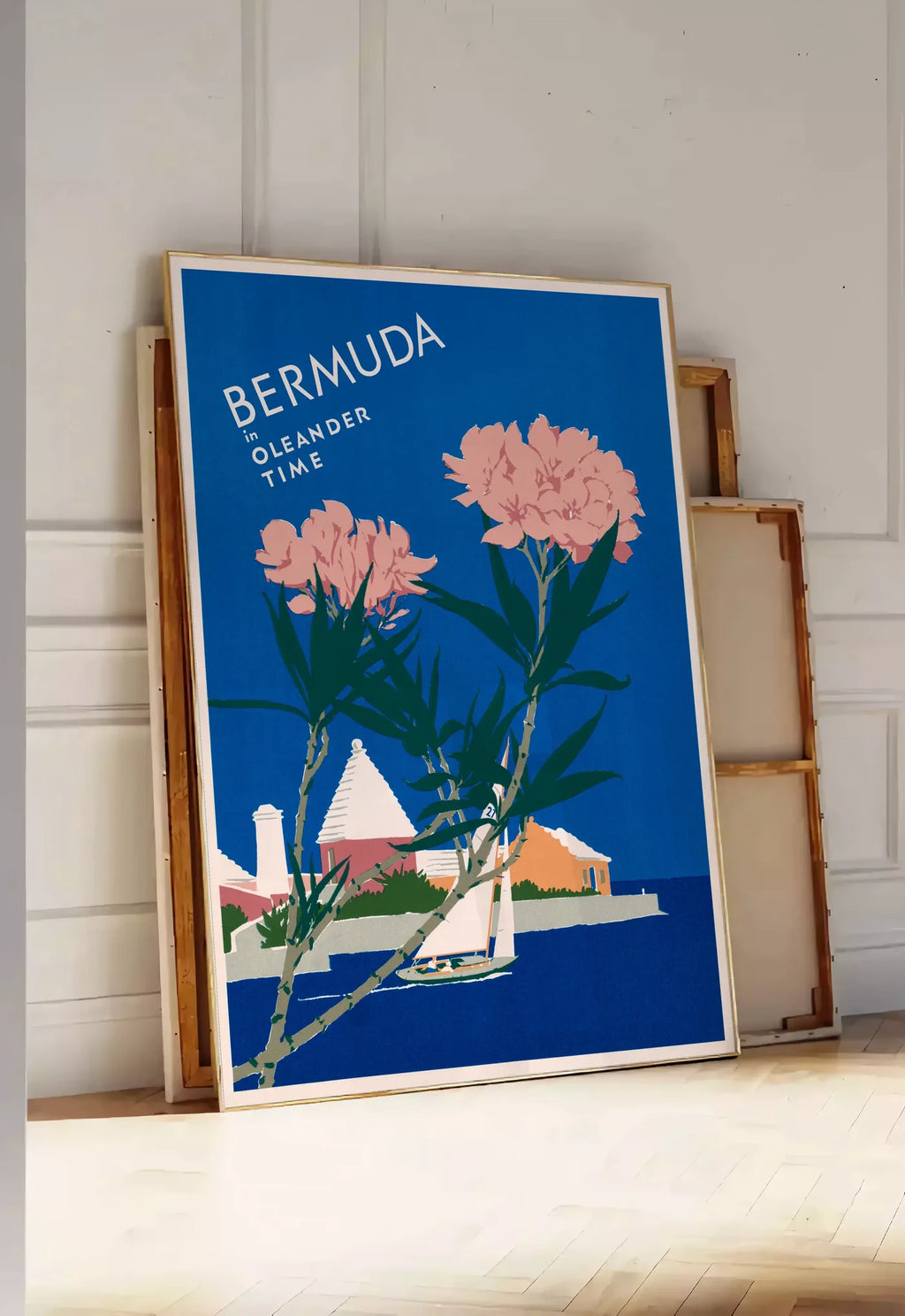 Tirage encadrable affiche Bermudes vintage, posee au sol dans une entree lumineuse, contre un mur a panneaux blancs, a cote de chassis en bois empiles