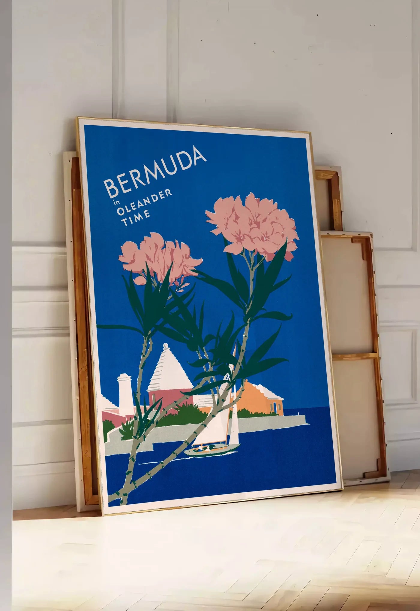 Tirage encadrable affiche Bermudes vintage, posee au sol dans une entree lumineuse, contre un mur a panneaux blancs, a cote de chassis en bois empiles