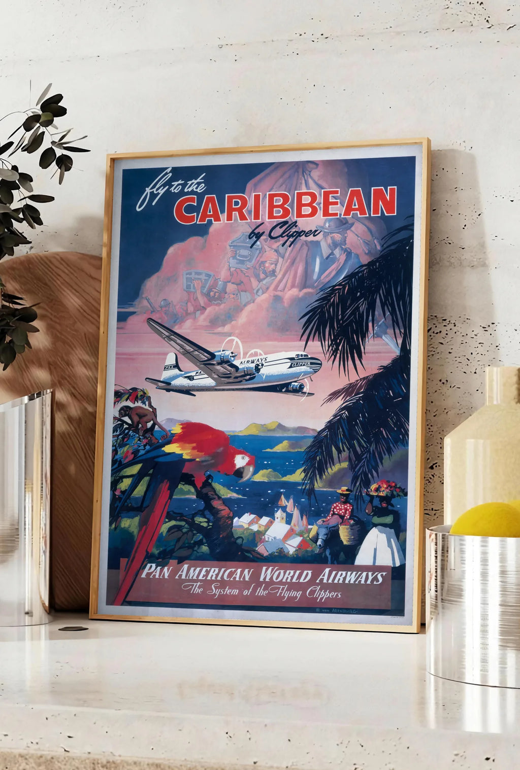 Affiche affiche Caraibes vintage, posee sur un plan de travail de cuisine en pierre claire, entre une branche d'eucalyptus en vase et un bocal de citrons