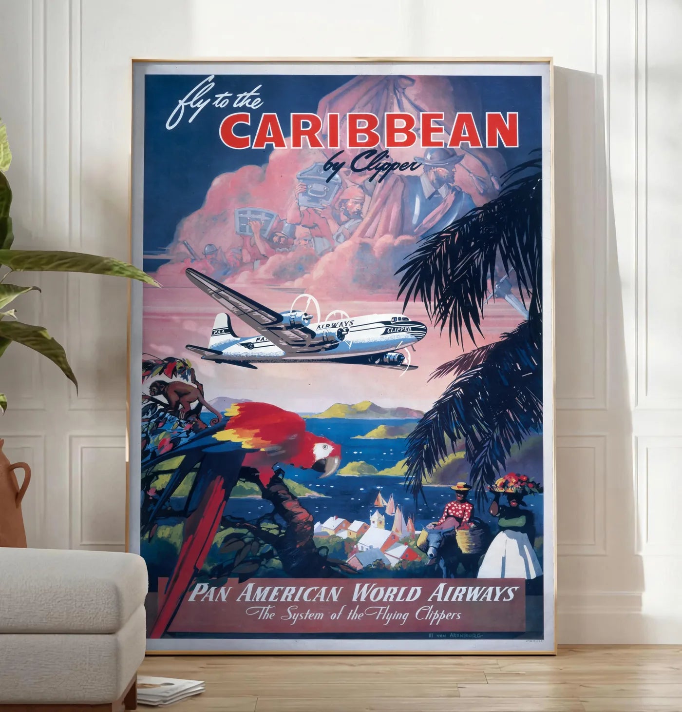 Reproduction affiche Caraibes vintage, posee au sol dans un salon minimaliste clair, a cote d'un canape beige et d'une plante verte, sur un parquet clair