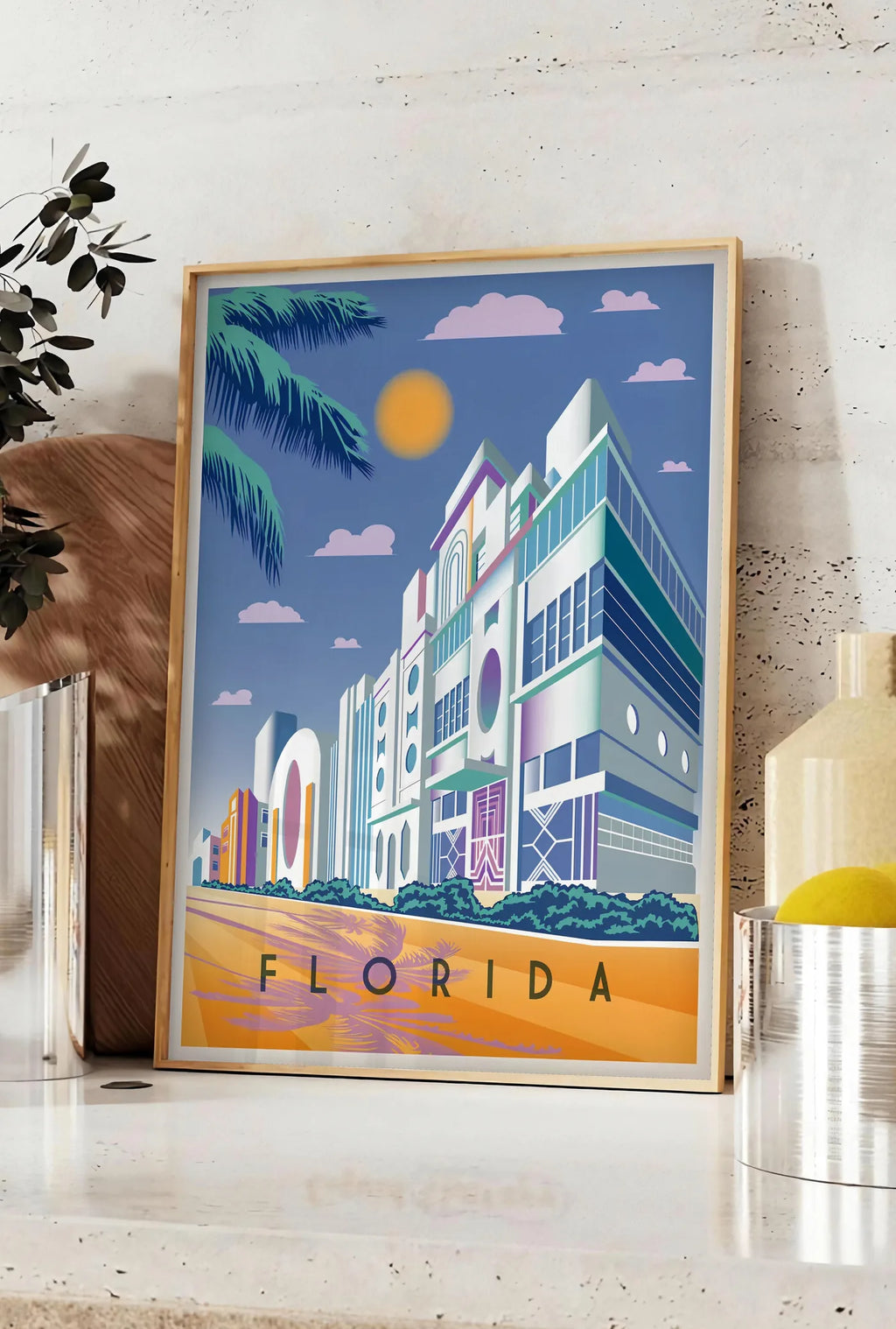 Affiche affiche Floride Art Deco, posee sur un plan de travail de cuisine en pierre claire, entre une branche d'eucalyptus en vase et un bocal de citrons
