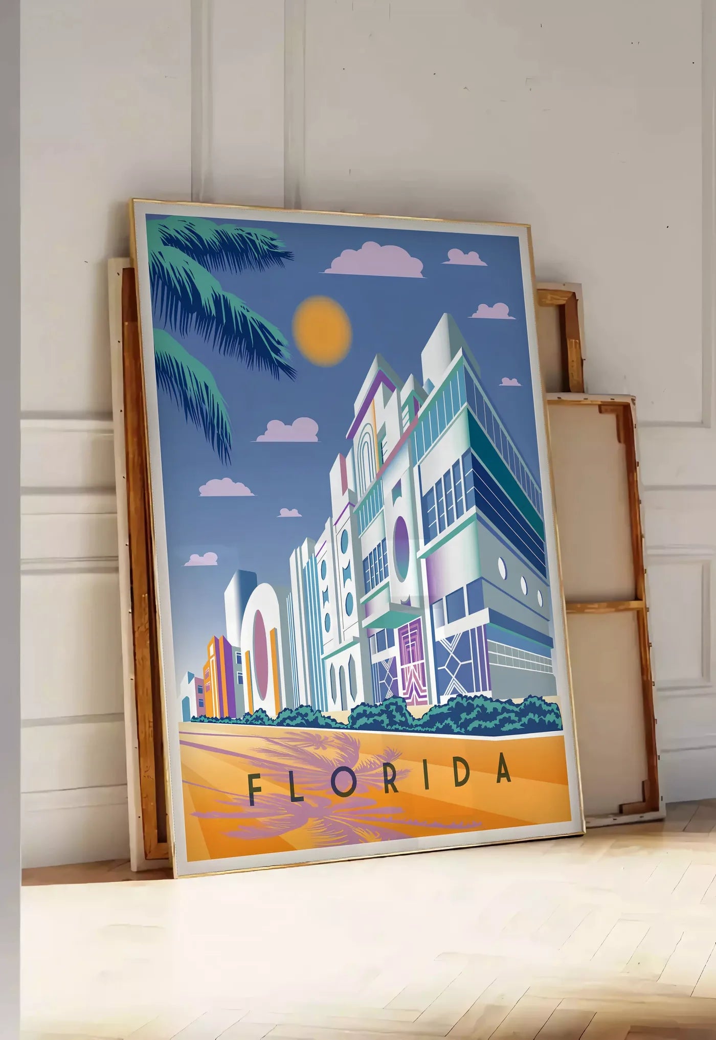 Tirage encadrable affiche Floride Art Deco, posee au sol dans une entree lumineuse, contre un mur a panneaux blancs, a cote de chassis en bois empiles