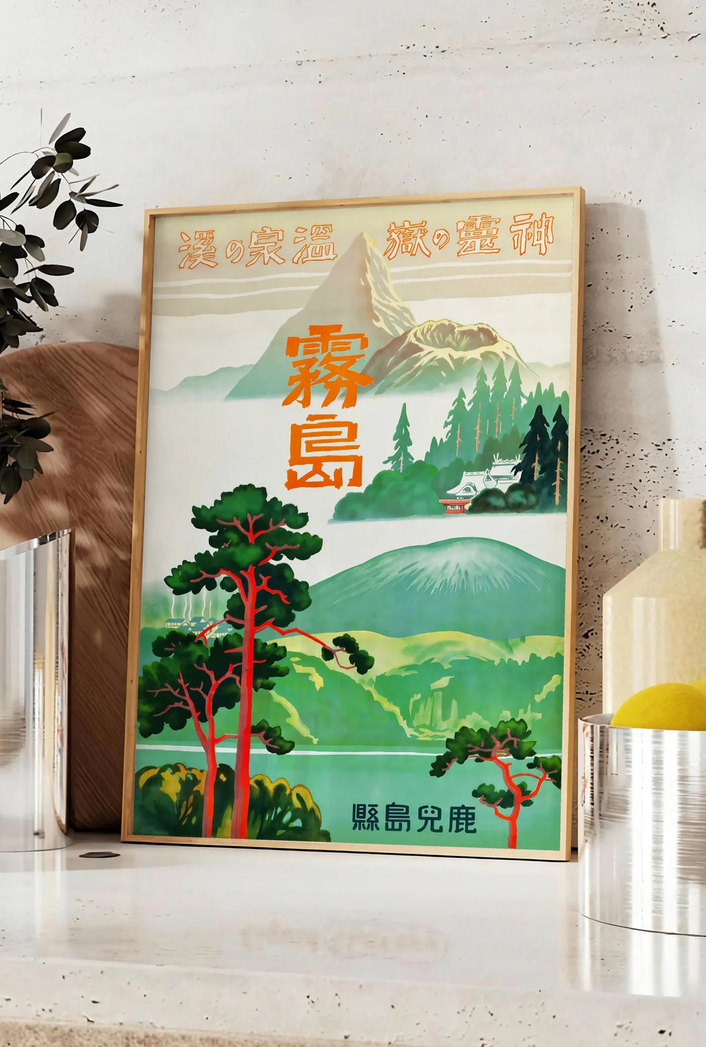 Affiche affiche Kirishima Japon vintage, posee sur un plan de travail de cuisine en pierre claire, entre une branche d'eucalyptus en vase et un bocal de citrons