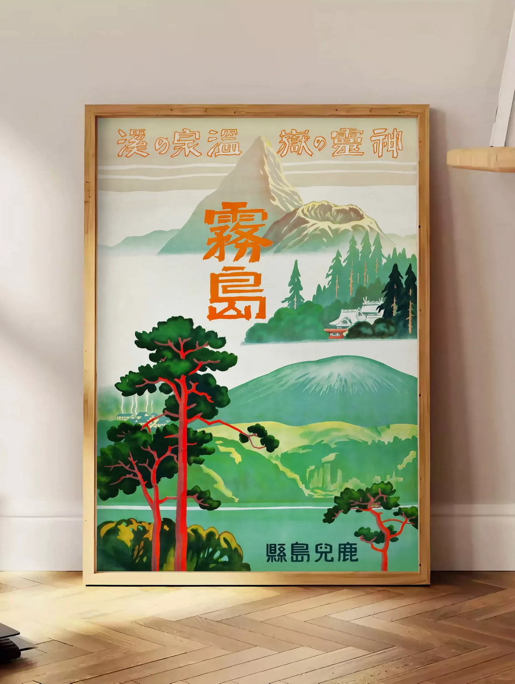 Estampe affiche Kirishima Japon vintage, posee au sol dans un coin salon, sur un parquet a chevrons, pres d'une table d'appoint en chene chargee de livres