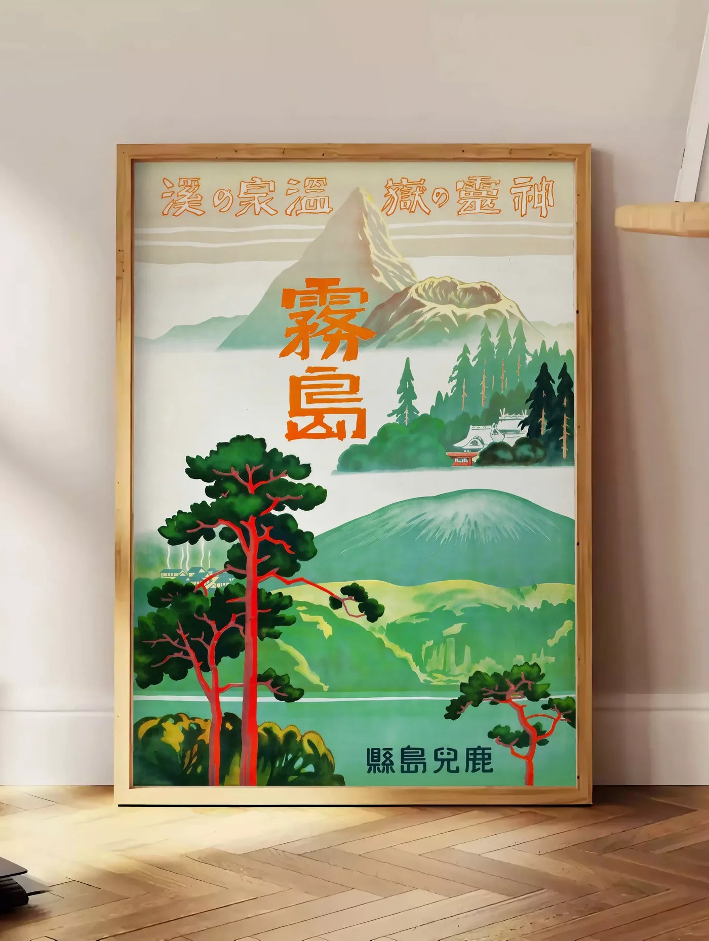 Estampe affiche Kirishima Japon vintage, posee au sol dans un coin salon, sur un parquet a chevrons, pres d'une table d'appoint en chene chargee de livres