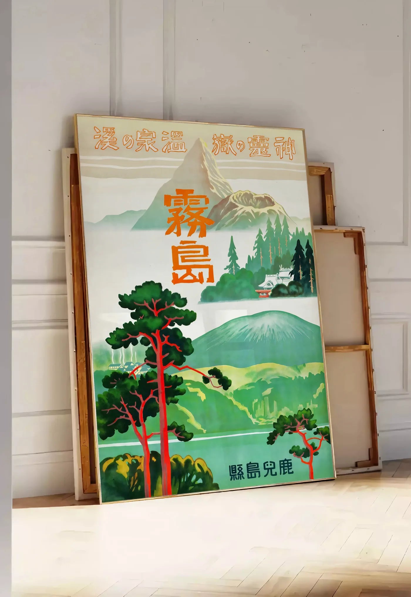 Tirage encadrable affiche Kirishima Japon vintage, posee au sol dans une entree lumineuse, contre un mur a panneaux blancs, a cote de chassis en bois empiles