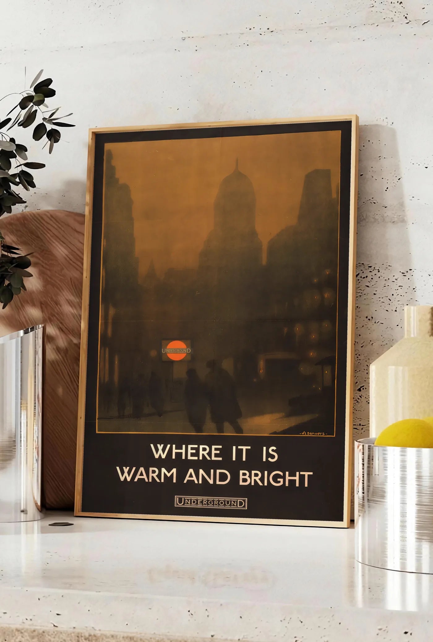 Affiche affiche Londres vintage, posee sur un plan de travail de cuisine en pierre claire, entre une branche d'eucalyptus en vase et un bocal de citrons