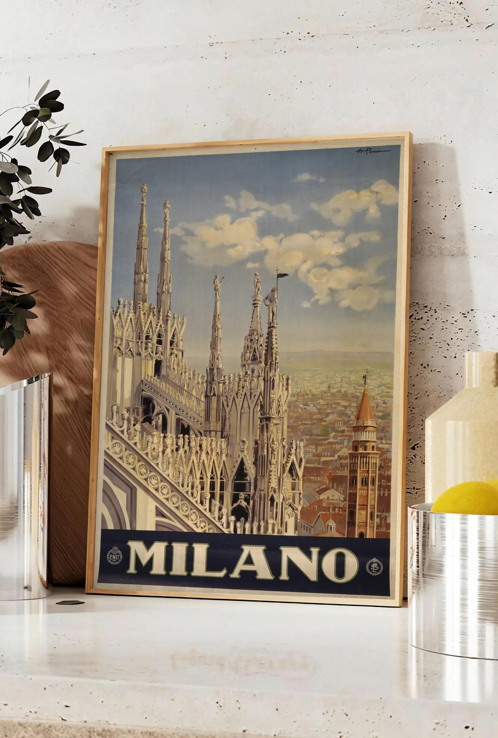 Affiche affiche Milano vintage, posee sur un plan de travail de cuisine en pierre claire, entre une branche d'eucalyptus en vase et un bocal de citrons