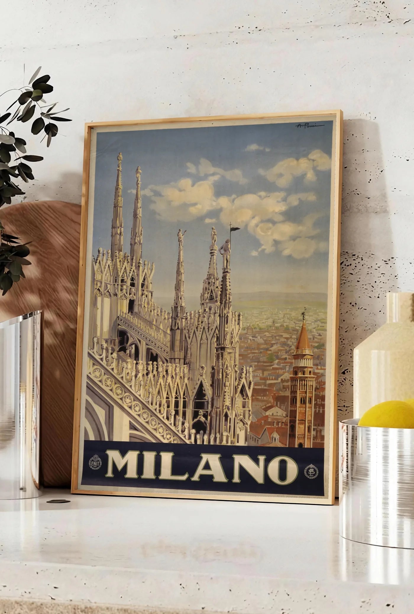 Affiche affiche Milano vintage, posee sur un plan de travail de cuisine en pierre claire, entre une branche d'eucalyptus en vase et un bocal de citrons