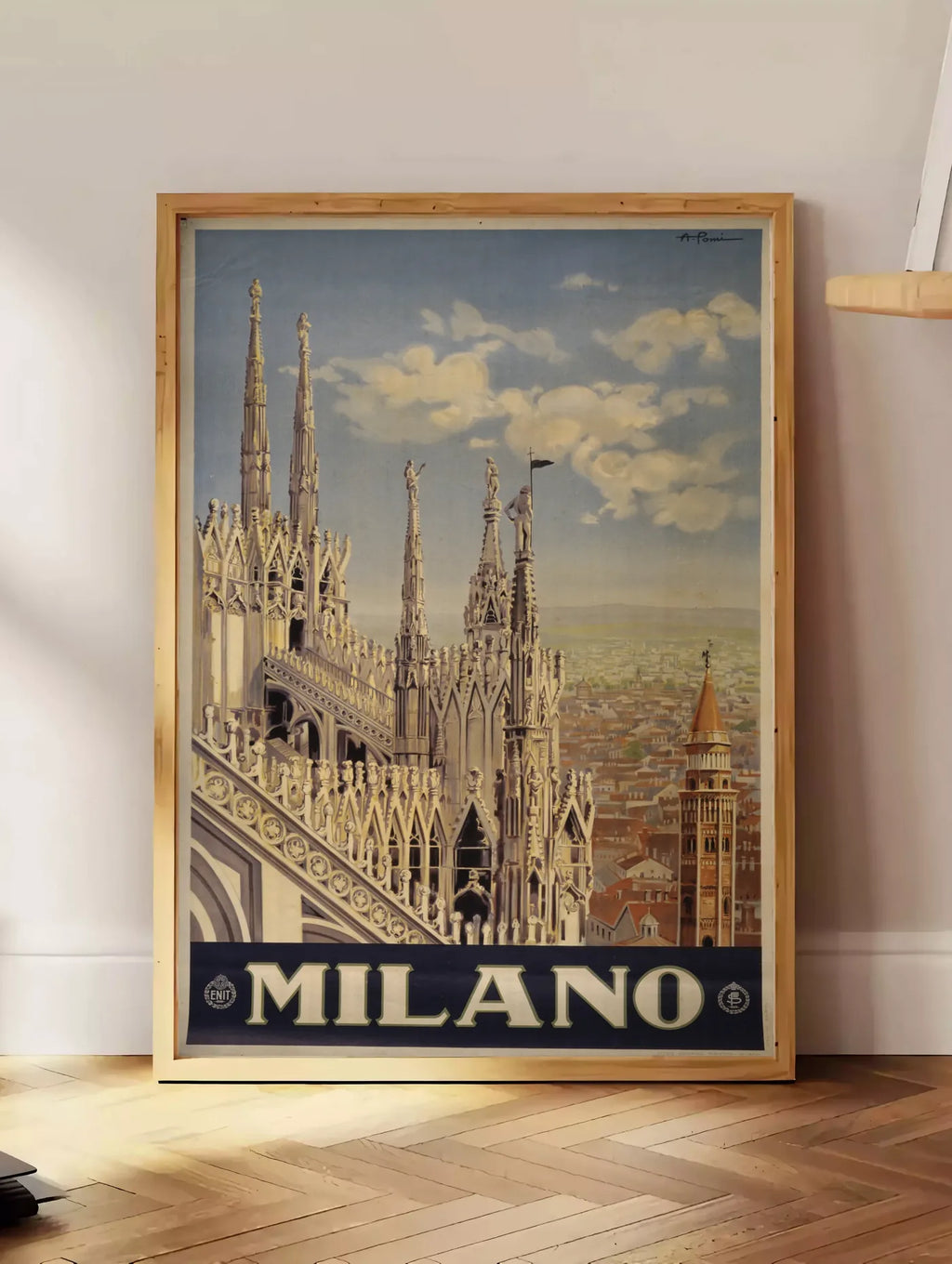 Estampe affiche Milano vintage, posee au sol dans un coin salon, sur un parquet a chevrons, pres d'une table d'appoint en chene chargee de livres