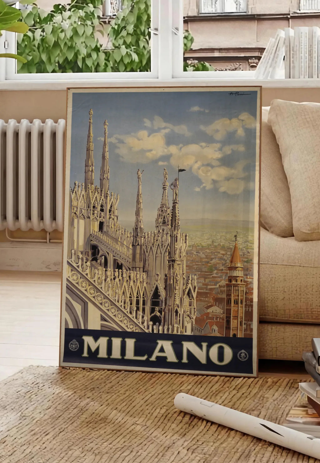 Poster affiche Milano vintage, posee au sol dans un salon parisien, devant une grande fenetre donnant sur un immeuble haussmannien, entre un ficus et un canape creme