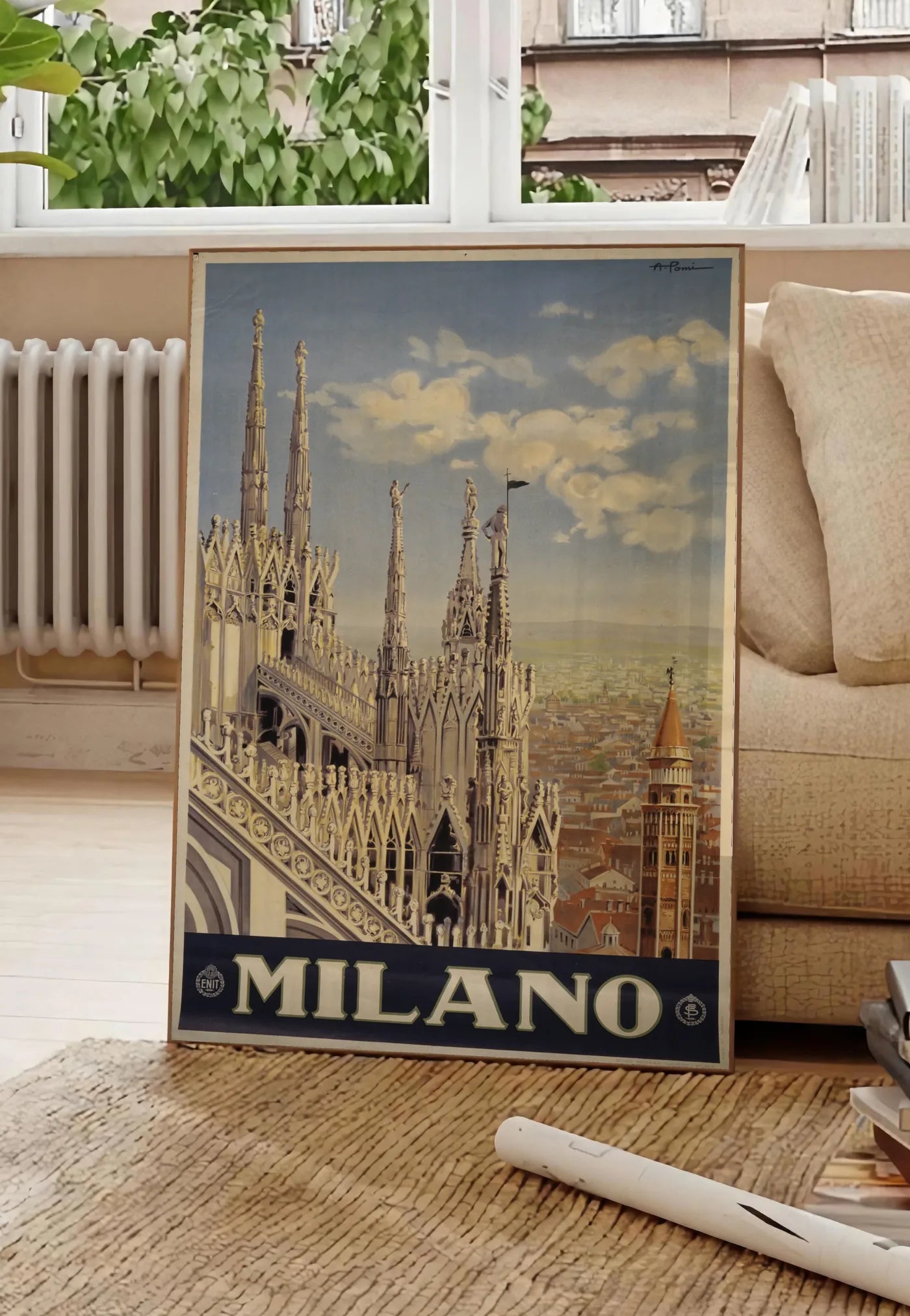 Poster affiche Milano vintage, posee au sol dans un salon parisien, devant une grande fenetre donnant sur un immeuble haussmannien, entre un ficus et un canape creme