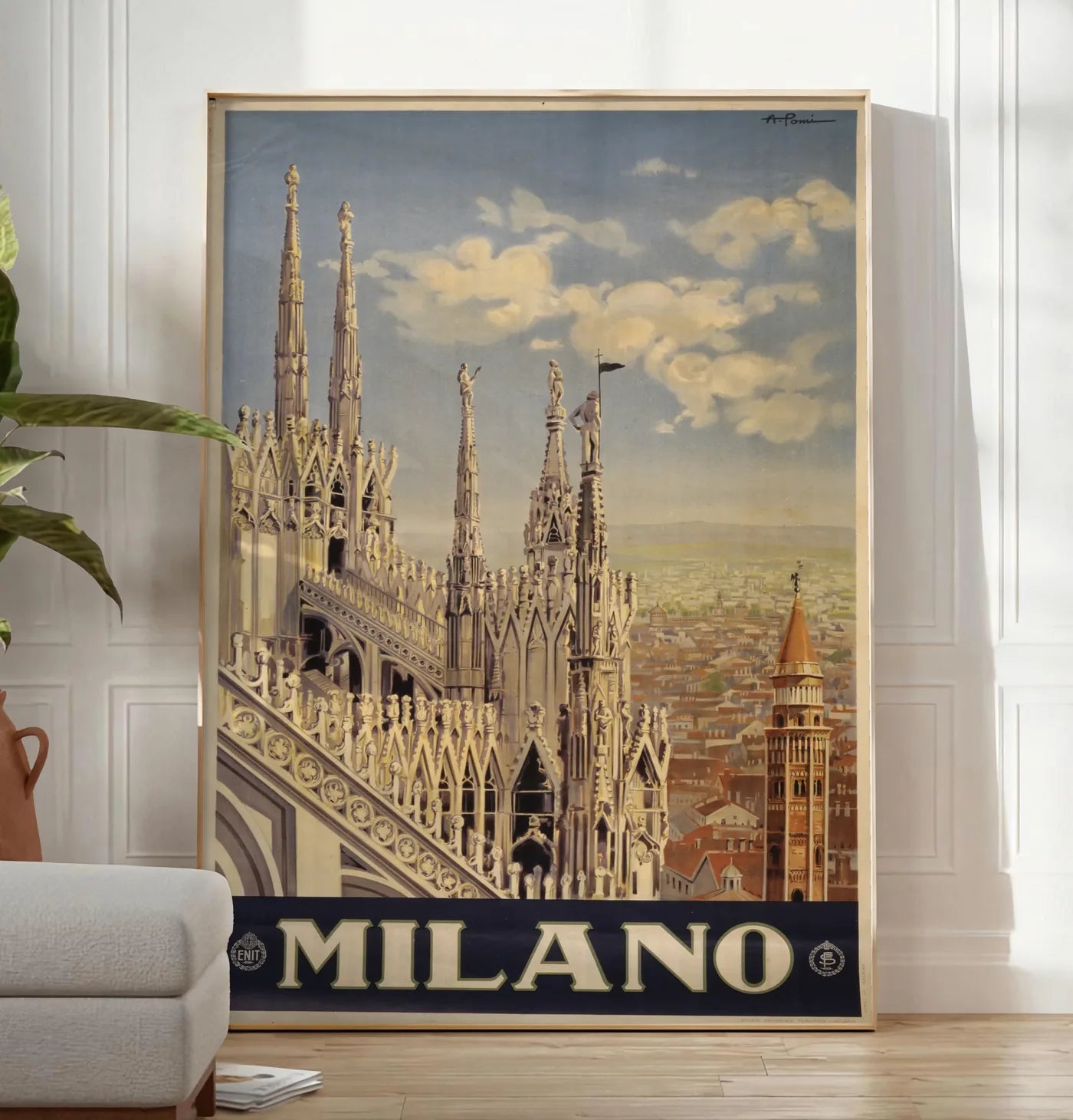Reproduction affiche Milano vintage, posee au sol dans un salon minimaliste clair, a cote d'un canape beige et d'une plante verte, sur un parquet clair