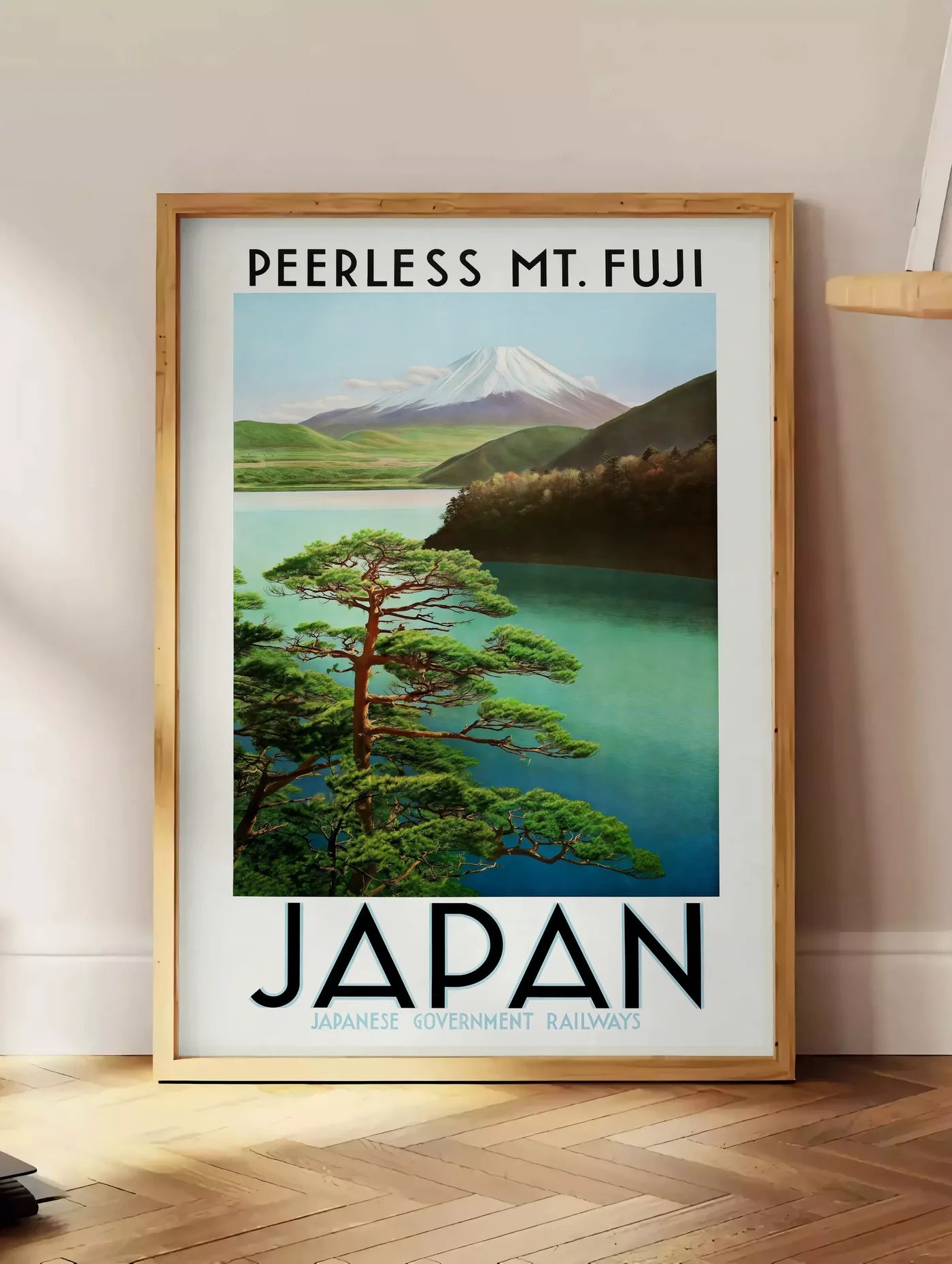 Estampe affiche mont Fuji voyage vintage art japonais, posee au sol dans un coin salon, sur un parquet a chevrons, pres d'une table d'appoint en chene chargee de livres