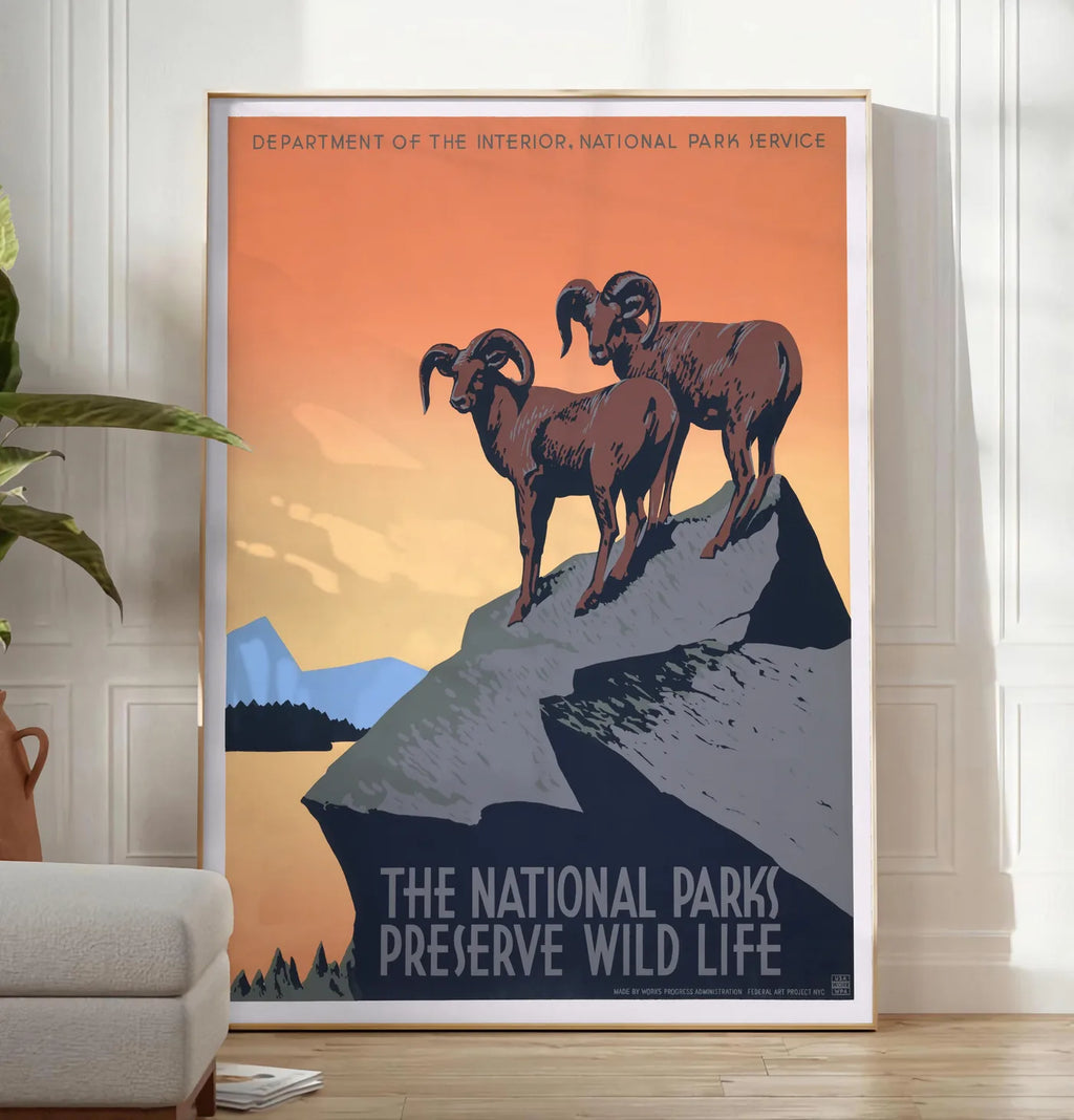 Reproduction affiche mouflons National Parks vintage, posee au sol dans un salon minimaliste clair, a cote d'un canape beige et d'une plante verte, sur un parquet clair