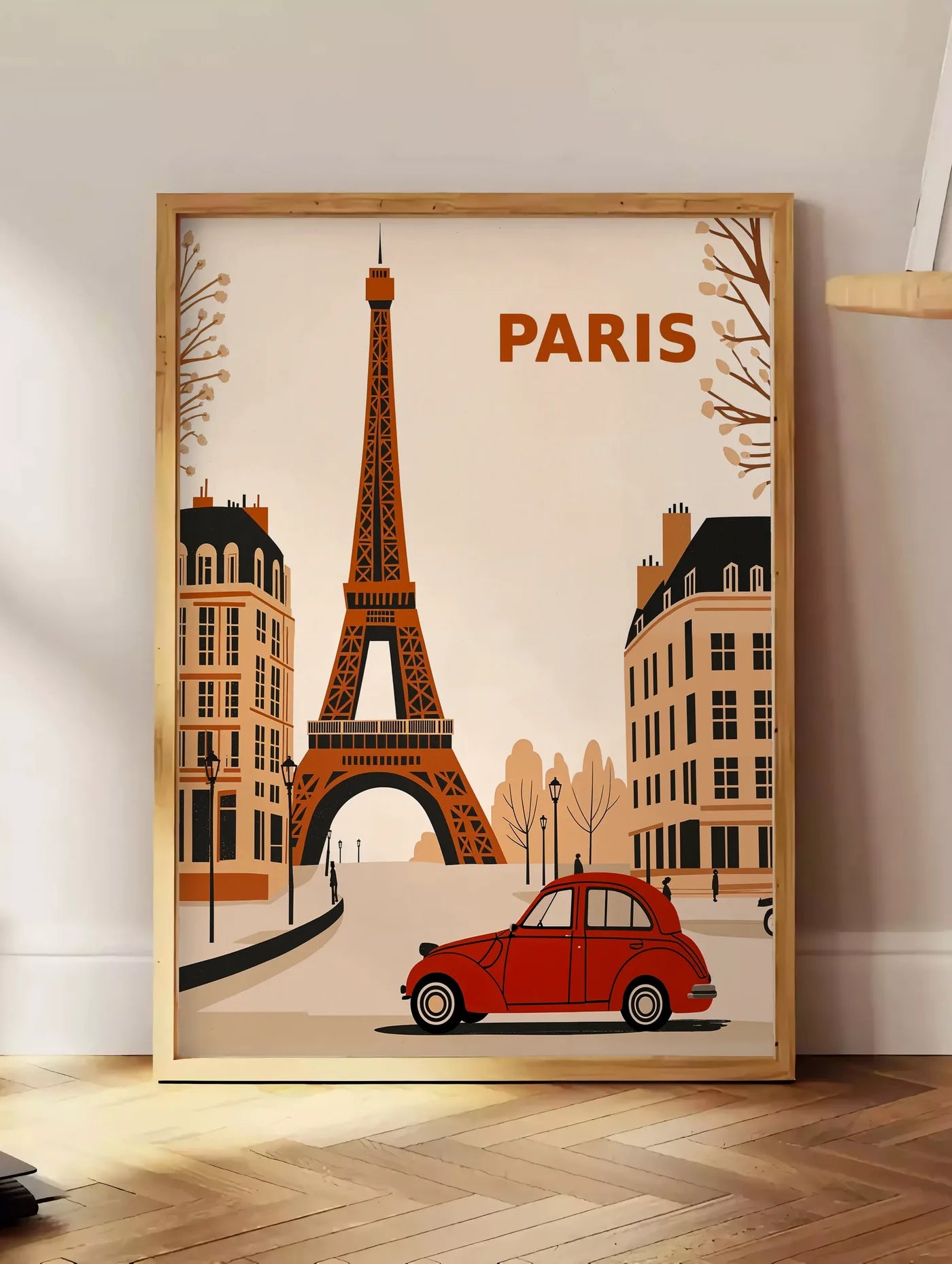 Estampe affiche Paris vintage, posee au sol dans un coin salon, sur un parquet a chevrons, pres d'une table d'appoint en chene chargee de livres