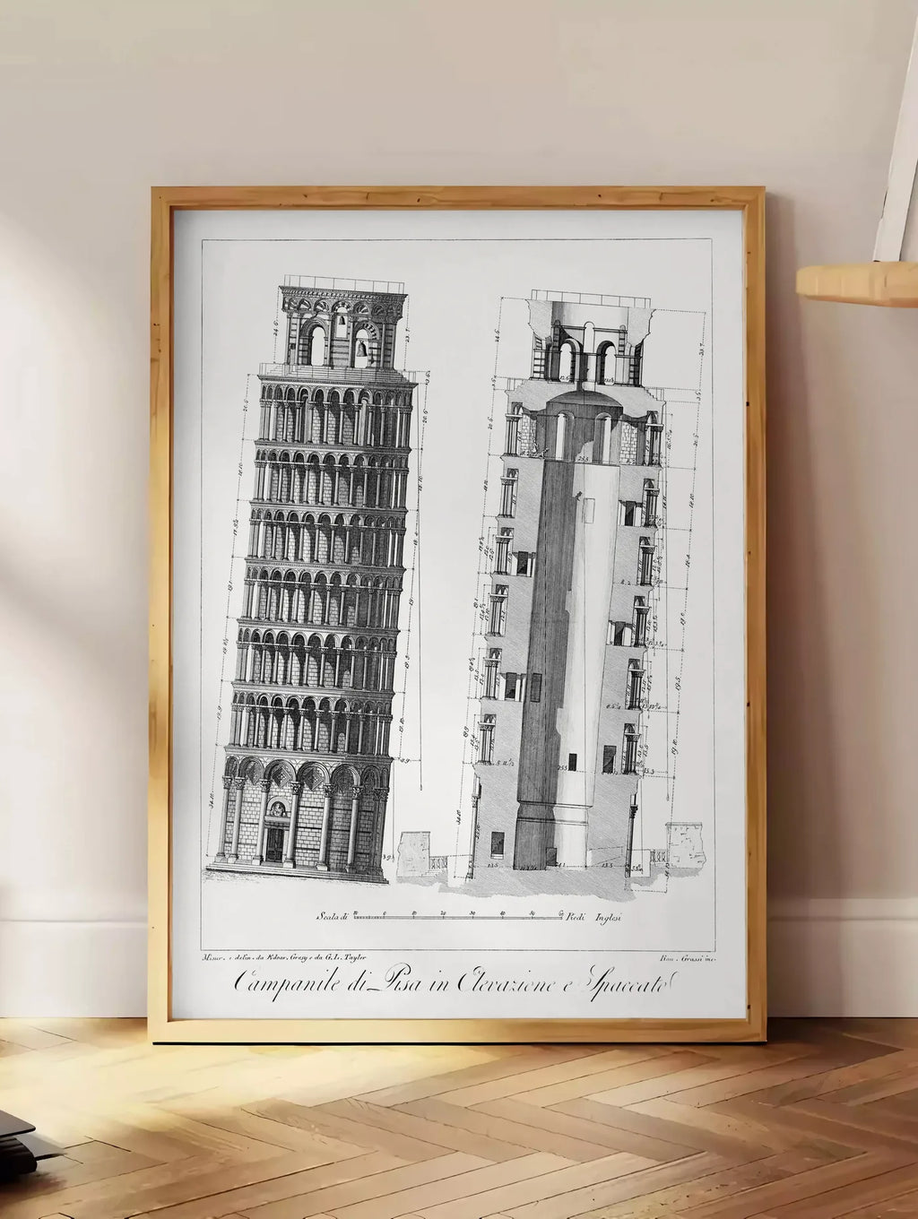 Estampe planche gravée Campanile de Pise montrant élévation et coupe, posee au sol dans un coin salon, sur un parquet a chevrons, pres d'une table d'appoint en chene chargee de livres