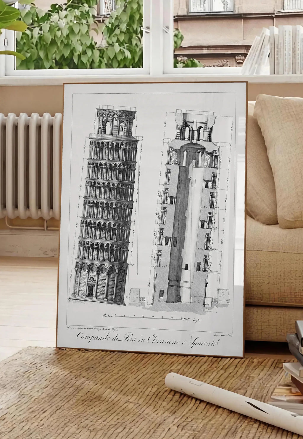 Poster planche gravée Campanile de Pise montrant élévation et coupe, posee au sol dans un salon parisien, devant une grande fenetre donnant sur un immeuble haussmannien, entre un ficus et un canape creme