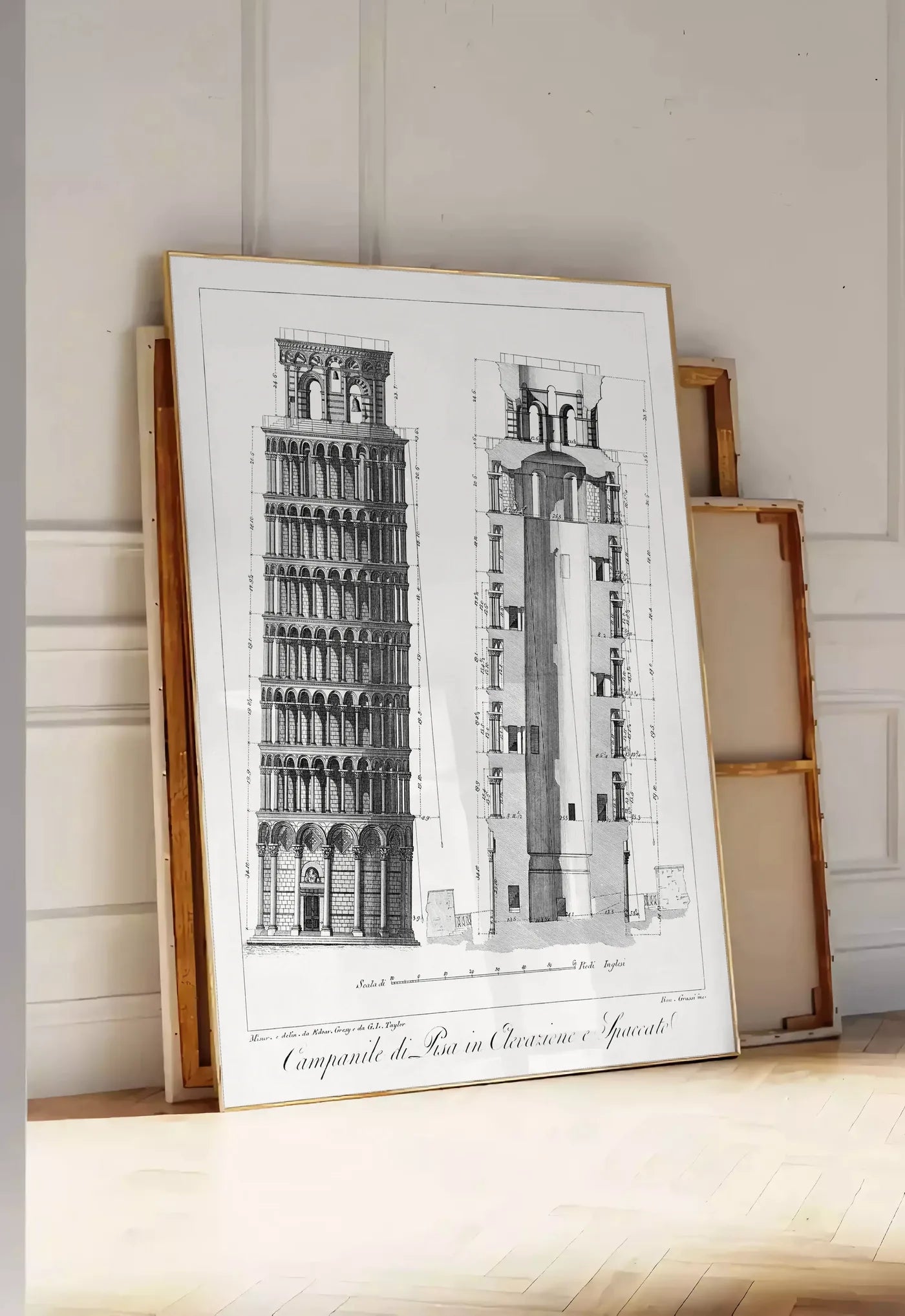 Tirage encadrable planche gravée Campanile de Pise montrant élévation et coupe, posee au sol dans une entree lumineuse, contre un mur a panneaux blancs, a cote de chassis en bois empiles