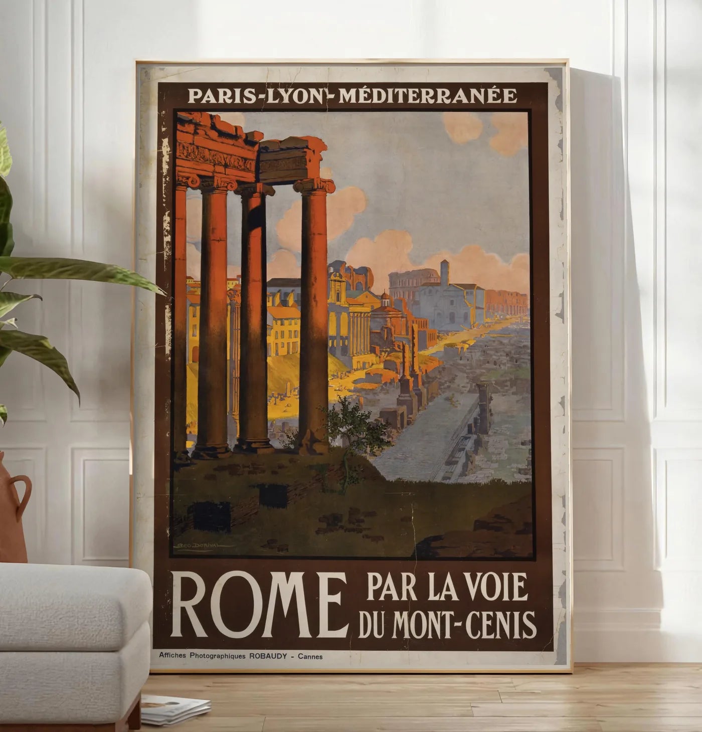 Reproduction affiche Rome vintage, posee au sol dans un salon minimaliste clair, a cote d'un canape beige et d'une plante verte, sur un parquet clair