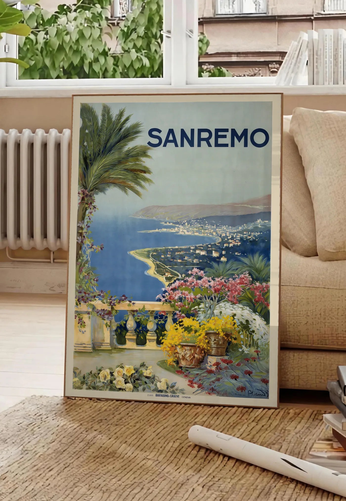 Poster affiche Sanremo vintage, posee au sol dans un salon parisien, devant une grande fenetre donnant sur un immeuble haussmannien, entre un ficus et un canape creme