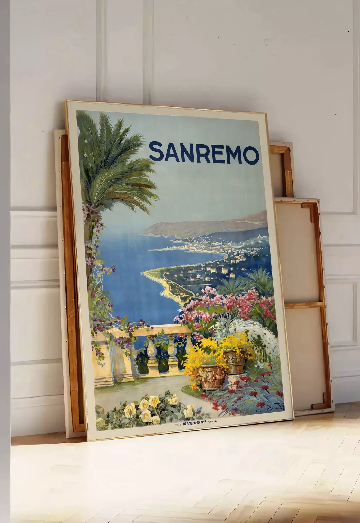Tirage encadrable affiche Sanremo vintage, posee au sol dans une entree lumineuse, contre un mur a panneaux blancs, a cote de chassis en bois empiles