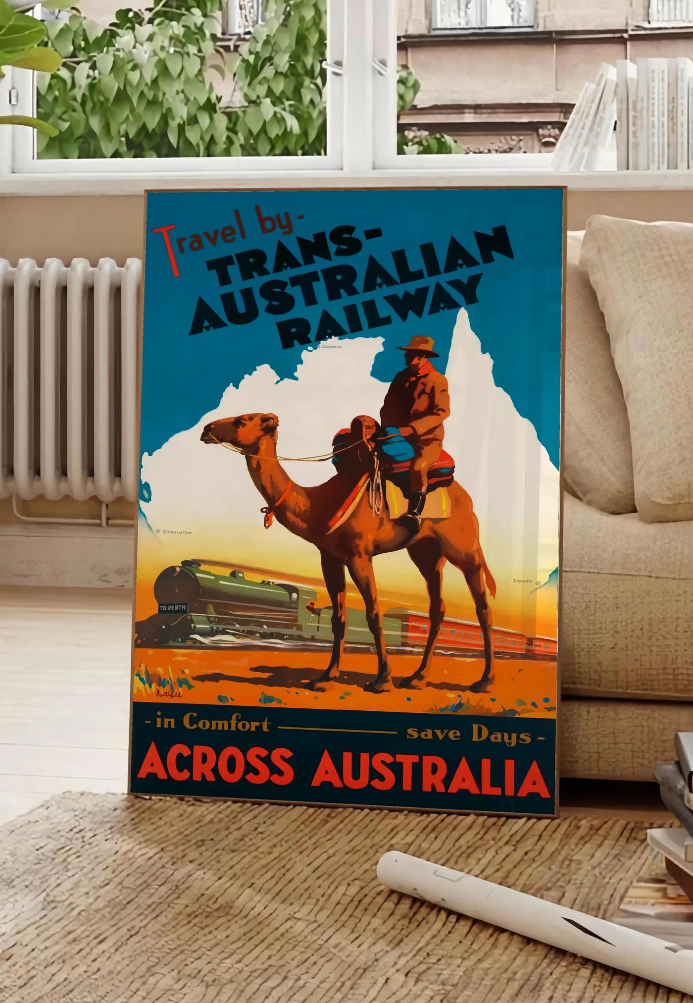 Poster affiche Australie vintage, posee au sol dans un salon parisien, devant une grande fenetre donnant sur un immeuble haussmannien, entre un ficus et un canape creme