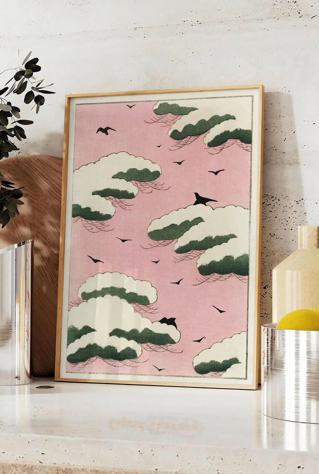 Affiche affiche nuages verts et oiseaux sur ciel rose de Watanabe Seitei estampe japonaise, posee sur un plan de travail de cuisine en pierre claire, entre une branche d'eucalyptus en vase et un bocal de citrons