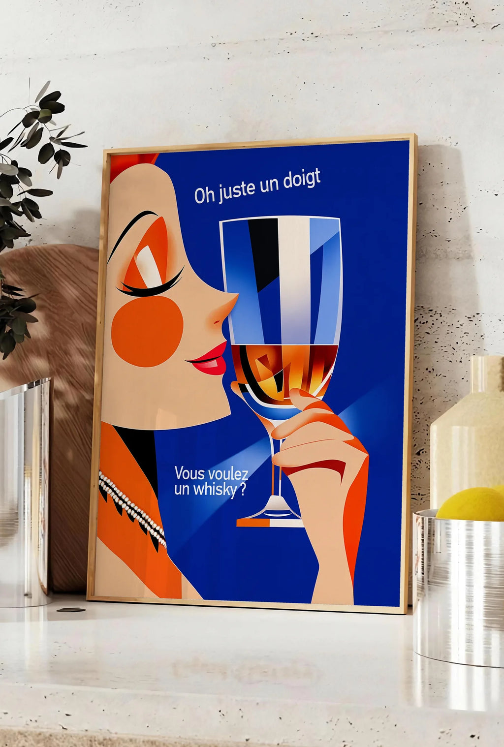 Affiche affiche cocktail whisky art deco, posee sur un plan de travail de cuisine en pierre claire, entre une branche d'eucalyptus en vase et un bocal de citrons
