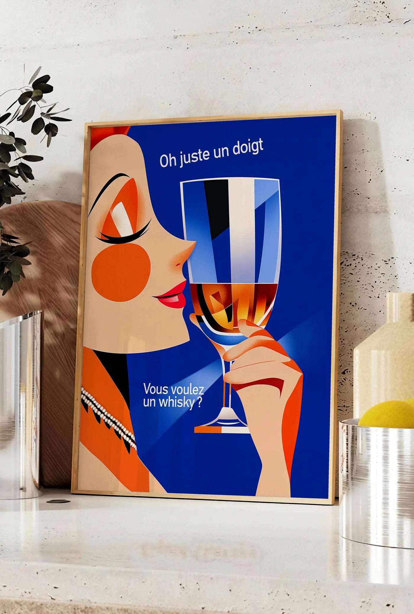 Affiche affiche cocktail whisky art deco, posee sur un plan de travail de cuisine en pierre claire, entre une branche d'eucalyptus en vase et un bocal de citrons