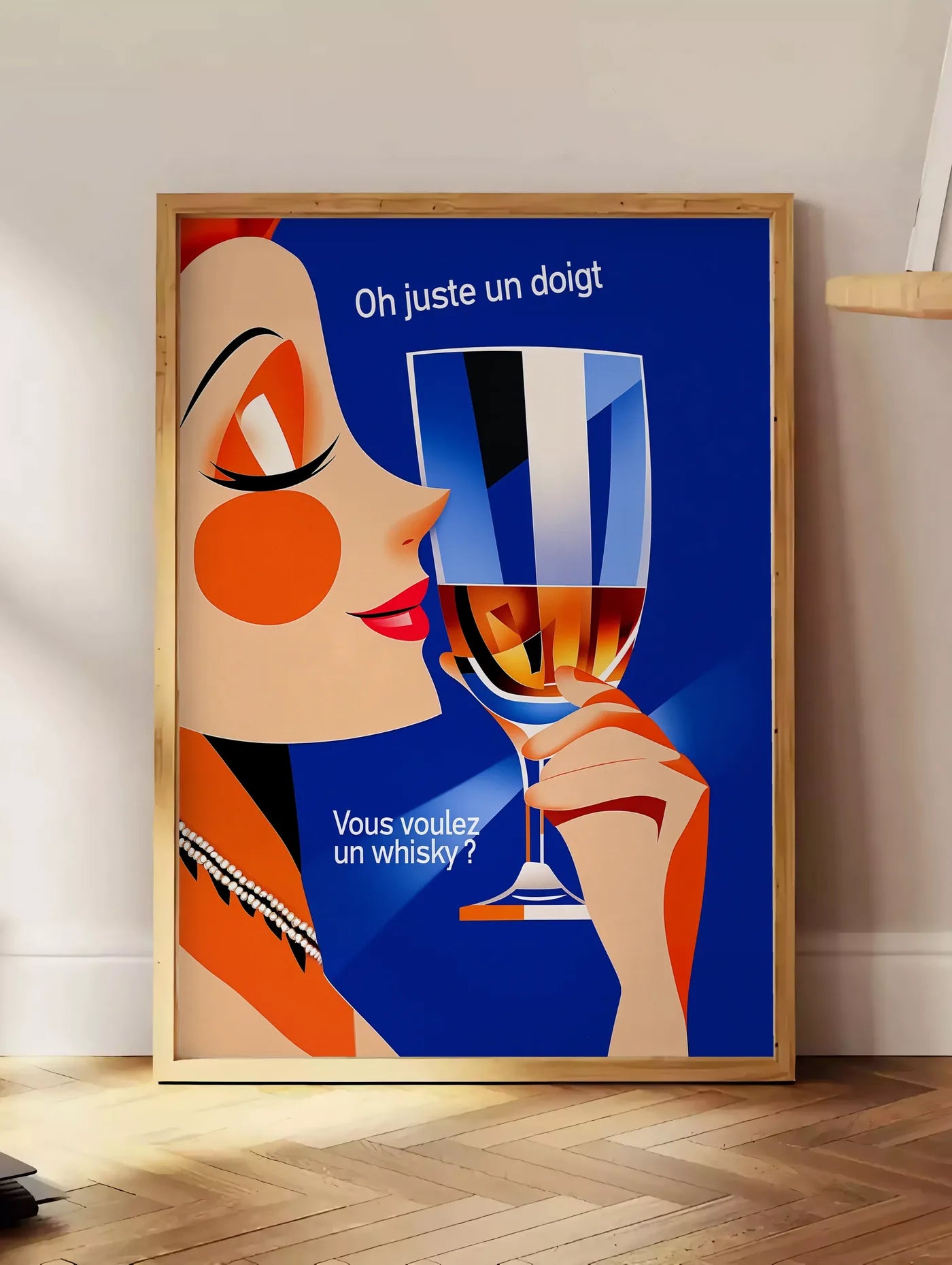 Estampe affiche cocktail whisky art deco, posee au sol dans un coin salon, sur un parquet a chevrons, pres d'une table d'appoint en chene chargee de livres