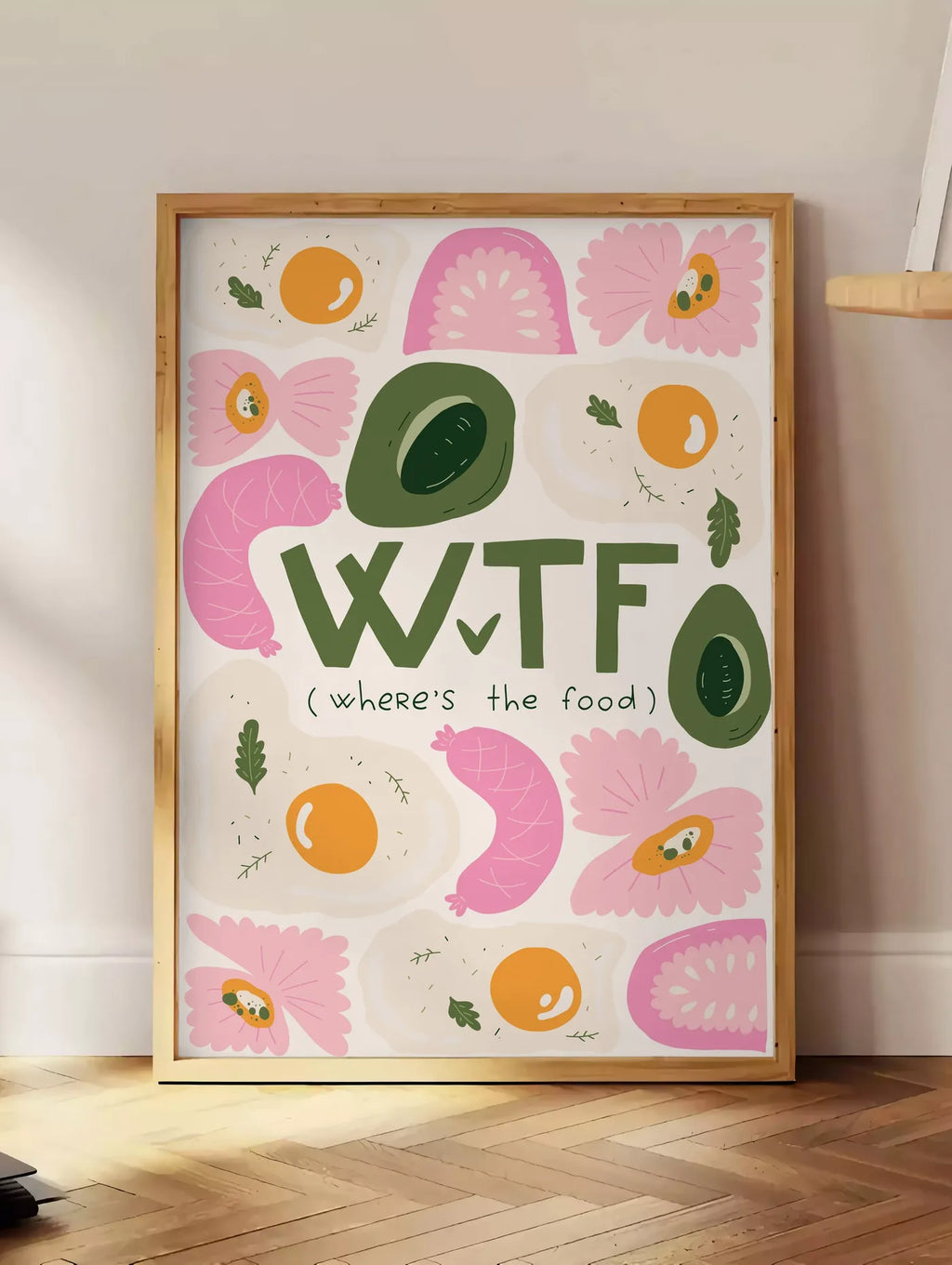 Estampe affiche cuisine food WTF, posee au sol dans un coin salon, sur un parquet a chevrons, pres d'une table d'appoint en chene chargee de livres