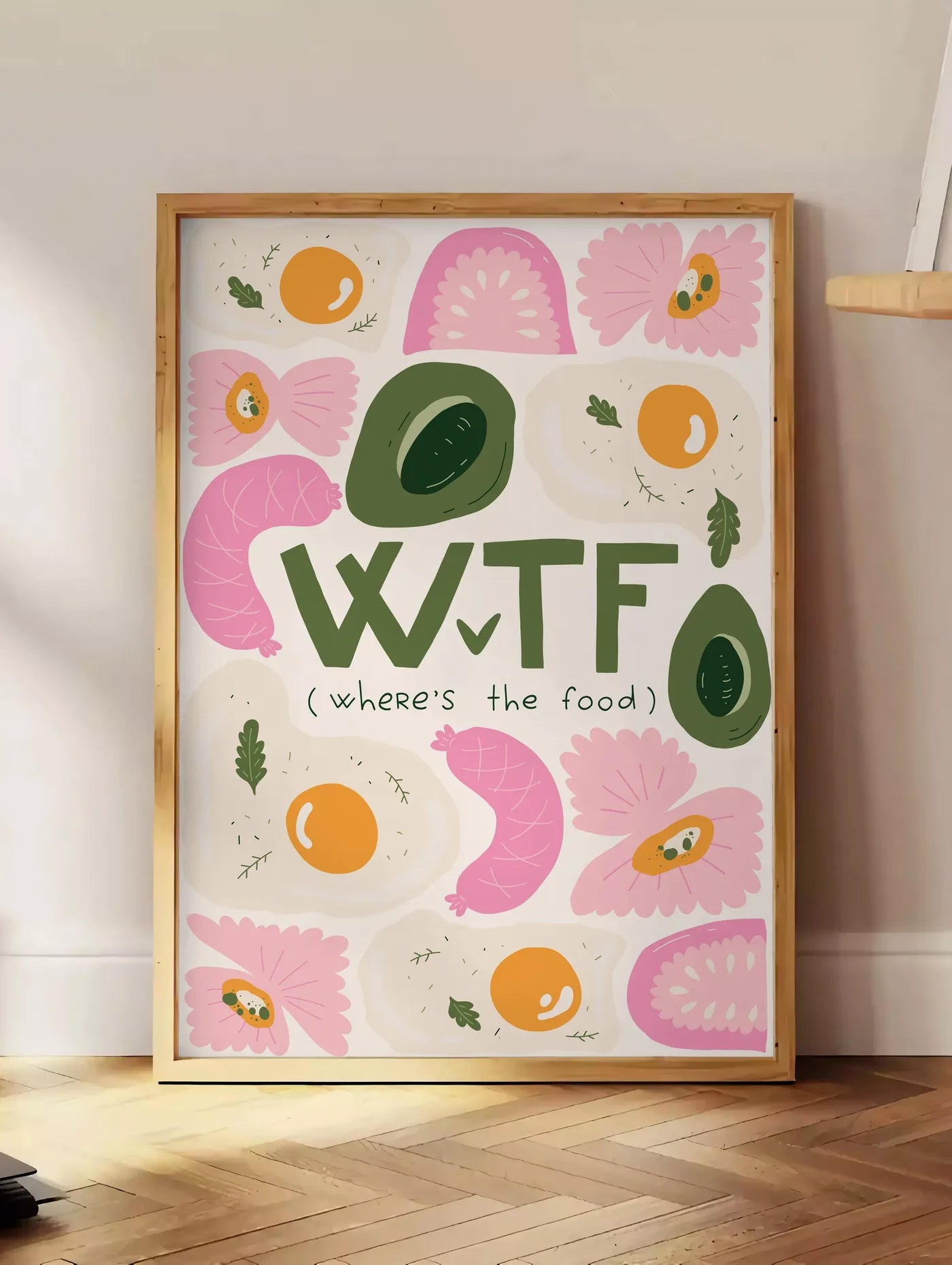 Estampe affiche cuisine food WTF, posee au sol dans un coin salon, sur un parquet a chevrons, pres d'une table d'appoint en chene chargee de livres