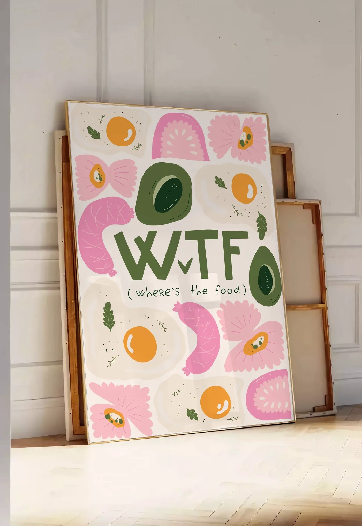 Tirage encadrable affiche cuisine food WTF, posee au sol dans une entree lumineuse, contre un mur a panneaux blancs, a cote de chassis en bois empiles